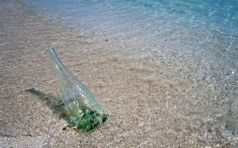 Обои Бутылка в песке у воды